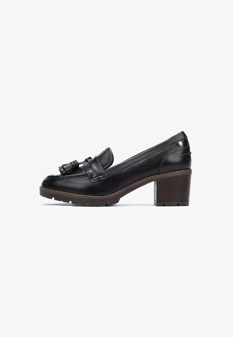 Mocassino in pelle nera con tacco basso a blocco, nappine decorative e suola texturizzata. Finitura liscia con un dettaglio di cuciture chiare a contrasto.