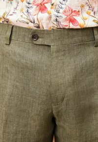 Oliwkowe lniane szorty z pojedynczym brązowym guzikiem, o gładkiej fakturze i płaskim przodzie.