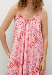 Rosa blomsterkjole med spaghetti-stropper. Har en samlet halsudskæring og flydende design, udsmykket med livlige orange og pink mønstre.