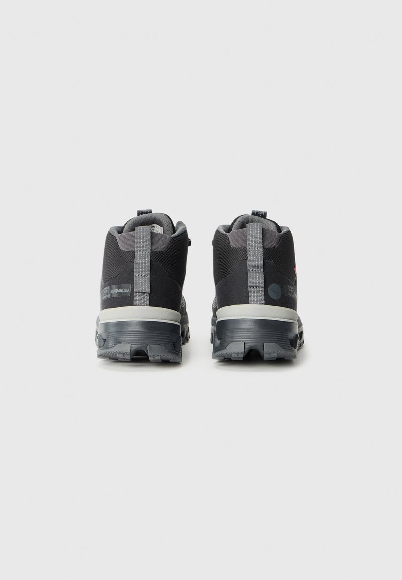 Schwarze Wanderschuhe mit einem grauen Obermaterial aus Stoff, strukturiertem Gummisohle und hinterer Schlaufe. Mit grauen Akzenten und einem gepolsterten Schaft für zusätzlichen Komfort.