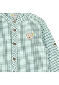 Camicia a quadri verde chiaro con colletto arrotondato, chiusura con bottoni di legno e toppa ricamata a forma di orso sul petto. Tessuto in cotone morbido.