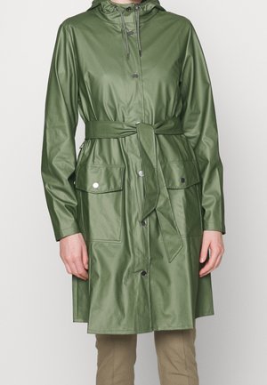 Manteau imperméable vert avec capuche, taille cintrée, design ceinturé et grandes poches avant. Texture lisse avec fermetures à boutons-pression.