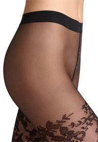 Primo piano dell'anca e della gamba di una persona che indossa collant neri trasparenti con un motivo in pizzo floreale vicino alla coscia e una vita solida.