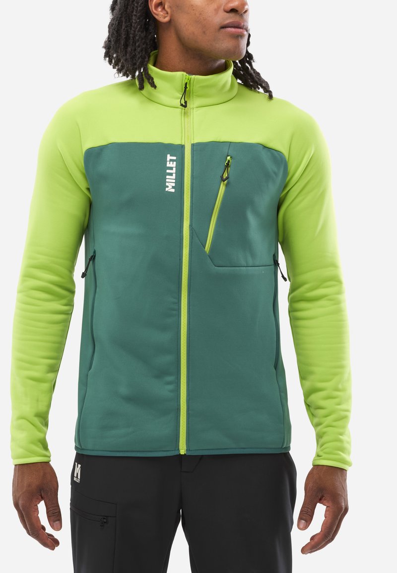 Grüne und limonengrüne Zip-Jacke mit hohem Kragen, ausgestattet mit einer Brusttasche und Seitentaschen, hergestellt aus einem glatten, dehnbaren Stoff.