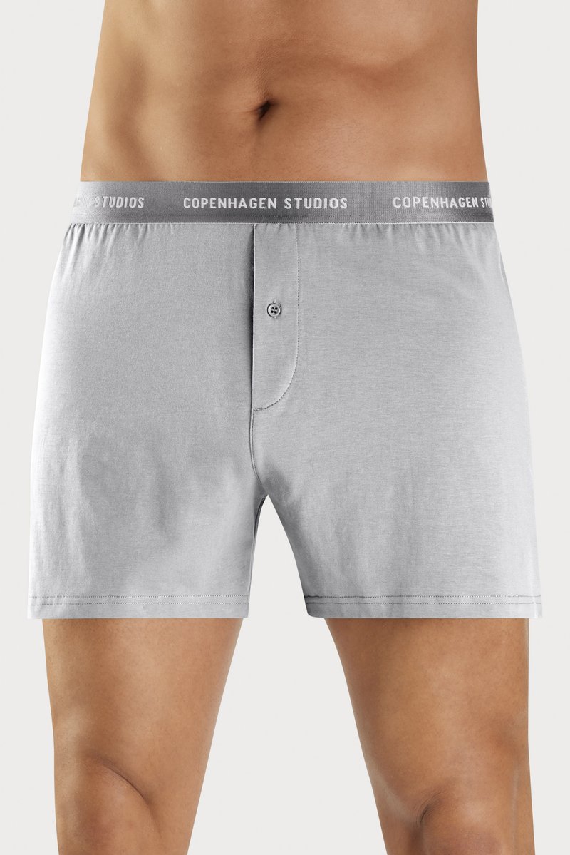 Grå bomull boxershorts med myk elastisk midjebånd med "COPENHAGEN STUDIOS" merking og knappefly. Glatt tekstur og tettsittende design.