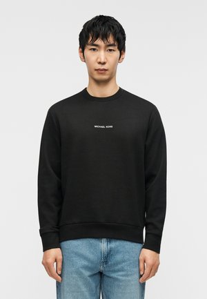 Schwarzer Sweatshirt mit Rundhalsausschnitt, mit einem weißen "MICHAEL KORS"-Logo auf der Brust. Weicher Stoff mit gerippten Bündchen und Saum.