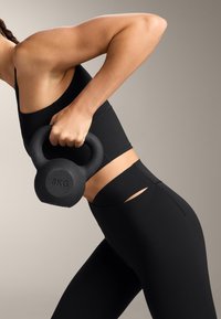 Čierny 8 kg kettlebell držaný v ruke, s čiernym športovým oblečením s výrezmi a hladkou matnou textúrou.
