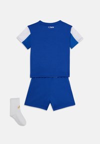 Equipamento juvenil de futebol do FC Porto em azul, apresentando uma camisa de manga curta com detalhes em branco e azul, calções a condizer e uma meia branca com logotipo dourado.