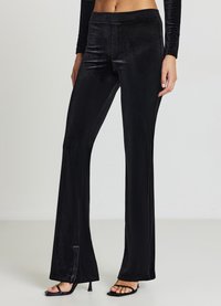 Pantalon évasé en velours noir avec une texture lisse, doté d'une fente latérale à l'ourlet et d'une taille ajustée. Conçu pour une coupe sur mesure.