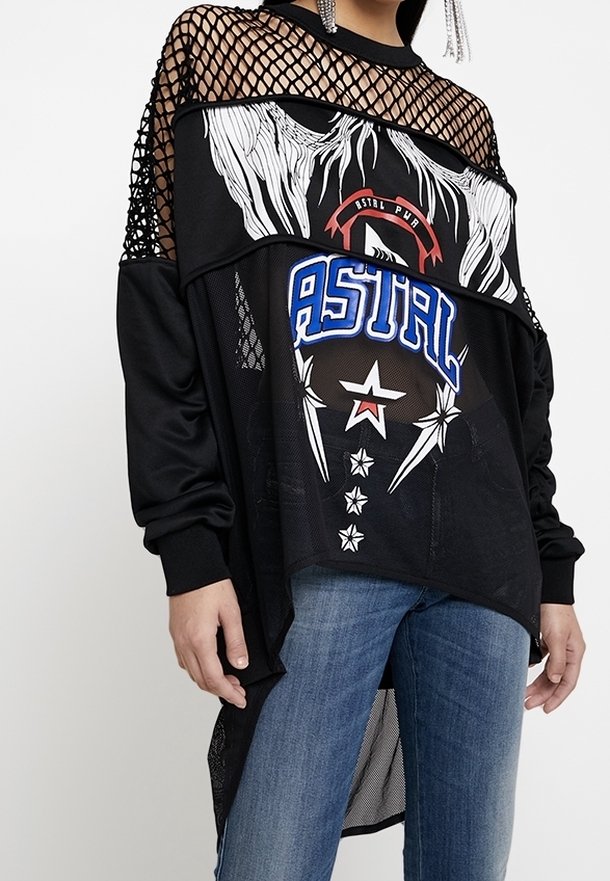 Personne porte un haut en mesh à manches longues noir avec des motifs graphiques blancs et bleus, associé à un jean bleu. Le détail en mesh couvre les épaules et la poitrine.