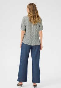 Korte mouwen shirt in groen en wit zigzagpatroon, gecombineerd met losse blauwe spijkerbroek, met een opgerolde zoom en een wijd model.