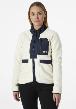 Fleece jack met een crèmekleurige basis en marine accenten. Voorzien van een ritssluiting, hoge kraag en twee voorzakken. Gelaagde textuur met contrasterende panelen.