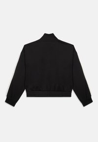 Sort cropped jakke med høj krave, elastiske manchetter og talje; har hvide sidelåse og glat stofoverflade.