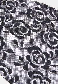 Μαύρο δαντέλα ύφασμα με ανθισμένο σχέδιο με τριαντάφυλλα, σε αντίθεση με λευκό φόντο. Πολύπλοκες λεπτομέρειες και ανοιχτή υφή πλέγματος.