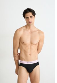 Fekete pamut alsónadrág rózsaszín Calvin Klein logós derékpánttal. A dizájn kontúros elejével és szoros illeszkedésével rendelkezik.