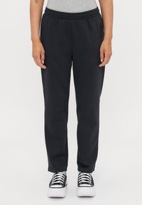 Pantaloni della tuta neri con vita elastica, caratterizzati da un dettaglio logo laterale. Abbinati a sneaker nere e bianche. Tessuto morbido e liscio.