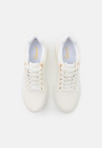 Weiße Sneaker mit einem glatten Lederoberteil, goldfarbenen Hardwareakzenten und weißen Schnürsenkeln. Das Innere hat einen gepolsterten Kragen für zusätzlichen Komfort.