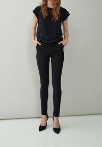 Svart kortärmad topp i kombination med svarta skinnybyxor och spetsiga svarta klackar. Outfiten har en avslappnad design med slim fit.