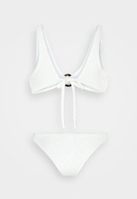 Conjunto de biquíni branco com um padrão de ondas texturizado, apresentando um top com decote em V e fecho de laço, e um detalhe redondo em dourado, além de parte de baixo correspondente.