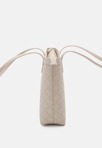 Beige handbag with a quilted diamond pattern, zip closure, and two thin straps. Smooth texture, structured shape, minimalist design.