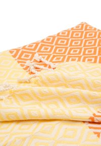 Cotton tæppe med et diamantmønster i orange og gult. Har knyttede frynser i den ene kant, tekstureret overflade med subtile detaljer.