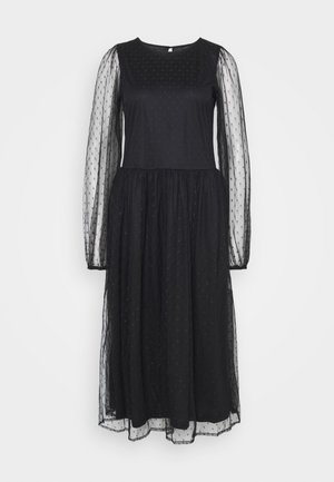 Czarna sukienka midi z przezroczystymi długimi rękawami i nakładką z wzorem w kropki, dopasowanym gorsetem i marszczonym dołem na jednolitym tle.