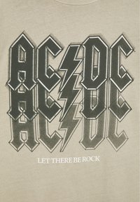 Logo du groupe AC/DC avec des lettres doubles et un éclair, avec le texte "Let There Be Rock" en dessous sur fond beige.