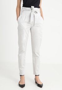 Lichtgrijze broek met een aansluitende taille, plooien en een stoffen riem. Gemaakt van soepel materiaal, met zijzakken en taps toelopende enkels.