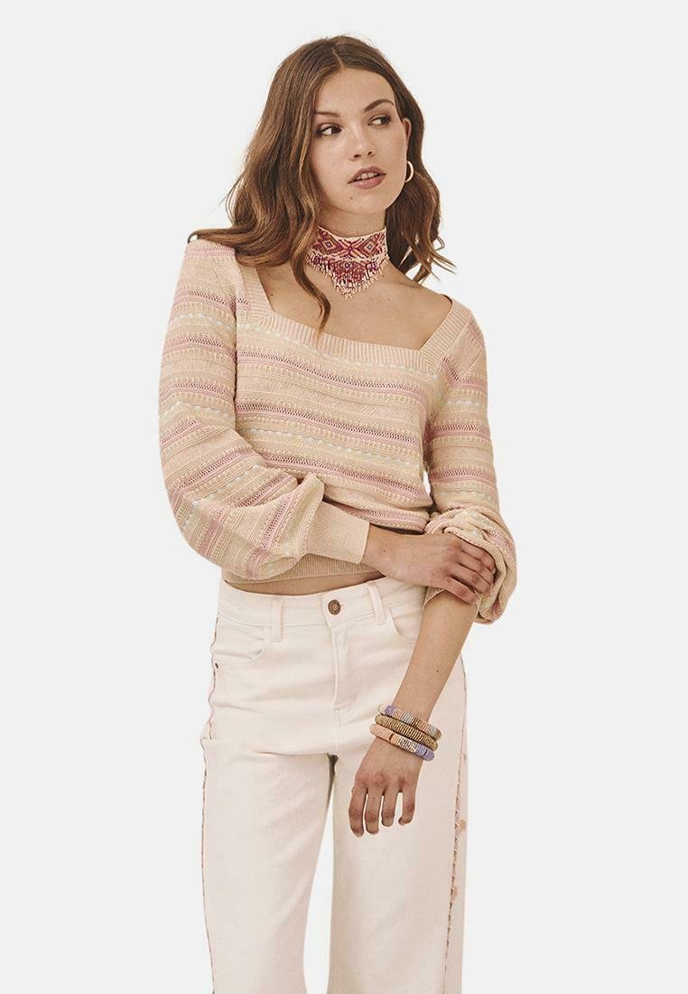 Suéter de punto con diseño off-shoulder, patrón a rayas en colores pastel, mangas globo, combinado con jeans blancos de tiro alto.