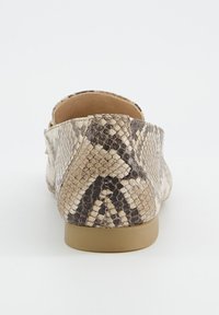 Zadní pohled na balerínu s béžovým a tmavě hnědým hadím vzorem a světle hnědou podrážkou na jednobarevném bílém pozadí.