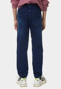 Pantalones jogger de mezclilla azul con un corte relajado y puños elásticos, que cuentan con una textura suave y dos bolsillos traseros.