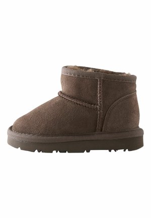 Bottines en suede marron avec une doublure en fourrure douce, bout rond et semelle en caoutchouc. Présente des coutures décoratives et un talon légèrement surélevé.