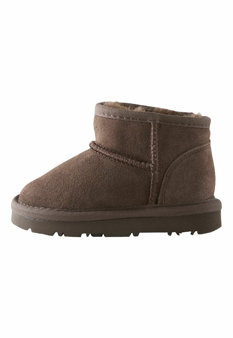 Braune Wildleder-Ankelstiefel mit einem weichen Fellfutter, runder Zehenpartie und einer Gummisohle. Sie verfügen über dekorative Nähte und einen leicht angehobenen Absatz.