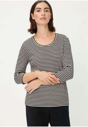 Langärmeliges Oberteil mit schwarzen und weißen Streifen, Rundhalsausschnitt, weiche Textur und figurbetontem Schnitt, kombiniert mit schwarzen Hosen.