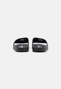 Black slide sandals with a textured rubber sole and dual straps. The interior features a logo and pattern detail along the side.