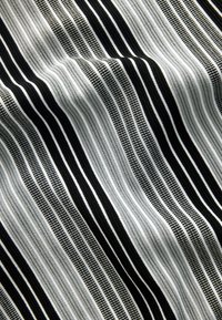 Schwarz-weiß gestreifter Stoff mit abwechselnd dicken und dünnen Linien, der ein strukturiertes Muster und eine glatte Oberfläche aufweist.