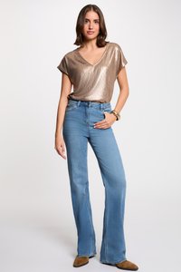 Top de bronce con escote en V y mangas cap, combinado con jeans acampanados de color azul claro. Botas de tobillo de ante marrón completan el conjunto. Textura suave en general.
