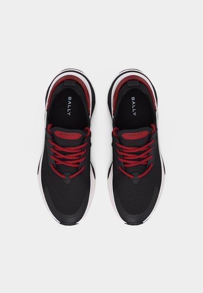 Paire de baskets noires Bally avec lacets rouges et détails rouges, semelles intermédiaires blanches et détails en mesh, vues de dessus sur un fond blanc.