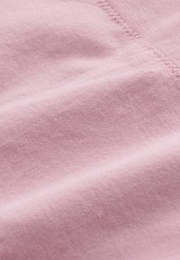 Tissu rose doux avec des coutures visibles, présentant une surface lisse, légèrement texturée et des plis délicats.