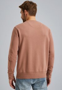 Bruine sweatshirt van zacht materiaal, met een ronde hals, lange mouwen en ribbelmanchetten. Lichtgewicht met een gladde textuur.