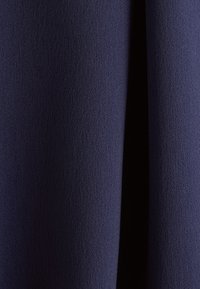 Tessuto di un blu scuro, con una trama testurizzata che presenta un motivo leggermente in rilievo, con una finitura morbida e liscia e un colore uniforme in tutto il tessuto.