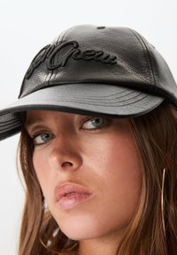 Czarna skórzana czapka z wypukłą haftowaną napisem "Crew", z zakrzywionym daszkiem i wyraźną fakturą, ustawiona pod lekkim kątem.