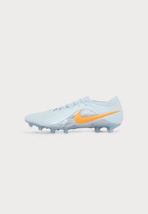 Chaussure de football bleu clair avec logo Nike orange, design texturé et crampons moulés sur la semelle pour jouer sur terrain ferme.