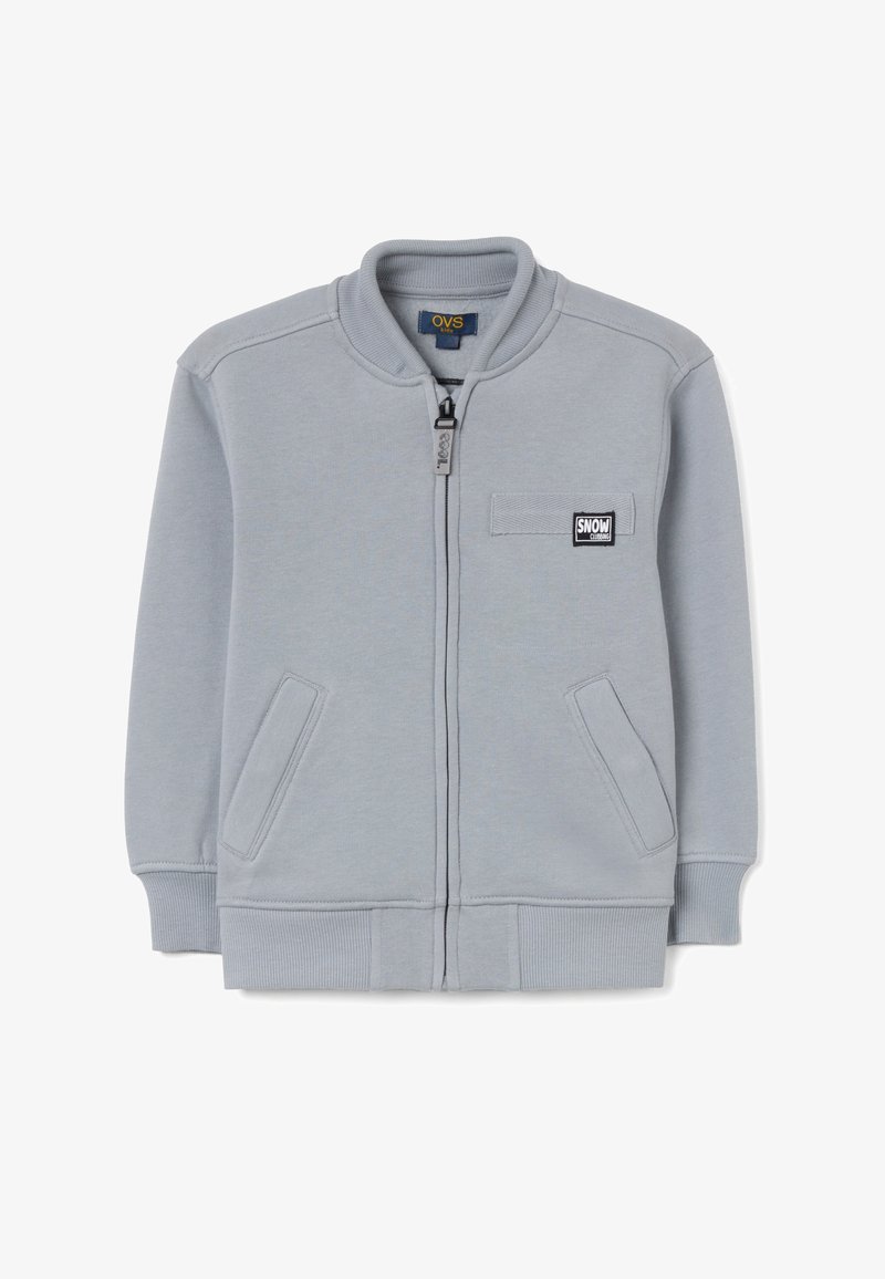 Sudadera gris con cremallera, cuello redondo, puños acanalados, bolsillos laterales y un pequeño parche rectangular "SNOW" en el pecho. Textura suave.