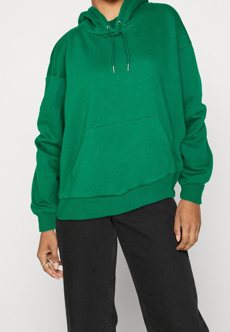 Sweat à capuche vert en tissu doux, doté d'une poche avant, de manches longues, d'une coupe décontractée et de poignets et ourlet côtelés.