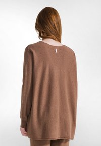 Brauner, übergroßer Strickpullover mit rundem Ausschnitt, strukturiertem Stoff und gerippten Bündchen. Verfügt über ein kleines Etikett am oberen Nacken.