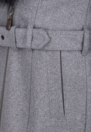 Section d'un manteau en laine grise montrant une ceinture à boucle et un détail de fermeture éclair avec une bordure en fourrure noire visible dans le coin supérieur gauche.