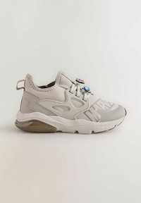 Des baskets en gris clair et blanc, présentant un matériau lisse, des découpes uniques, des accents texturés et des charms décoratifs sur les lacets.
