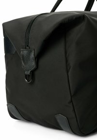 Mustan kankaan laukku, jossa on vetoketjukiinnitys; nahka-akkentteja; suorakulmainen muoto; pehmeä rakenne; harmaa alaosa on kontrastivärinen.