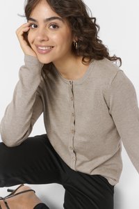 Beige gebreide cardigan met een ronde halslijn en knopen aan de voorkant. Heeft lange mouwen en een zachte textuur, gecombineerd met zwarte broek.